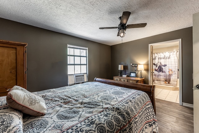 bedroom featuring a textured ceiling, hardwood / wood-style flooring, ensuite bath, and ceiling fan