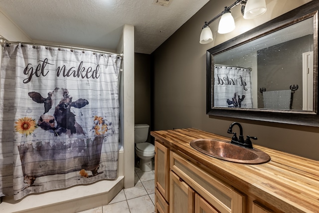 bathroom featuring tile patterned floors, toilet, a shower with curtain, vanity, and a textured ceiling