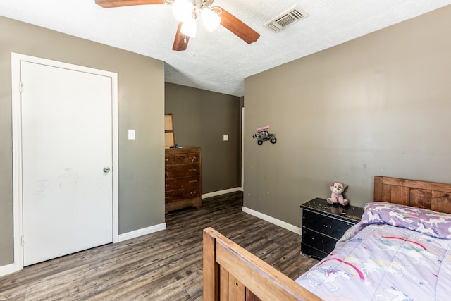 bedroom with ceiling fan, a textured ceiling, and dark hardwood / wood-style floors