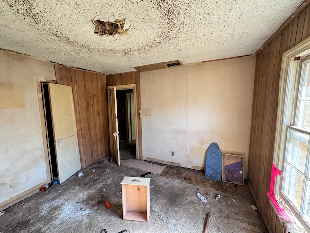 unfurnished bedroom featuring wooden walls and multiple windows