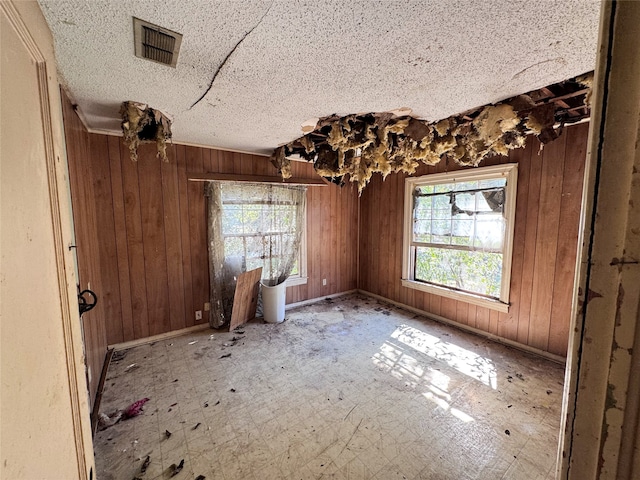 interior space with wooden walls and a textured ceiling