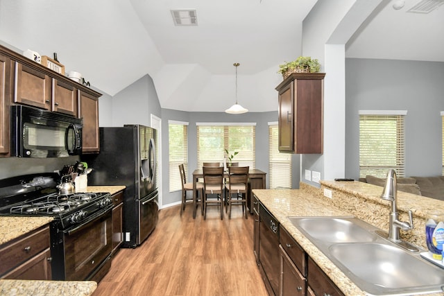 kitchen featuring lofted ceiling, light wood-type flooring, black appliances, pendant lighting, and sink