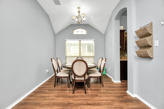 dining area with a notable chandelier, lofted ceiling, and dark hardwood / wood-style flooring