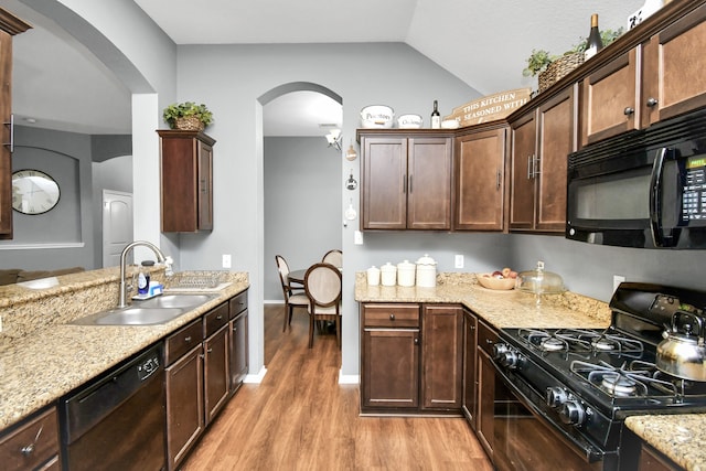 kitchen with lofted ceiling, dark brown cabinets, sink, black appliances, and light hardwood / wood-style floors