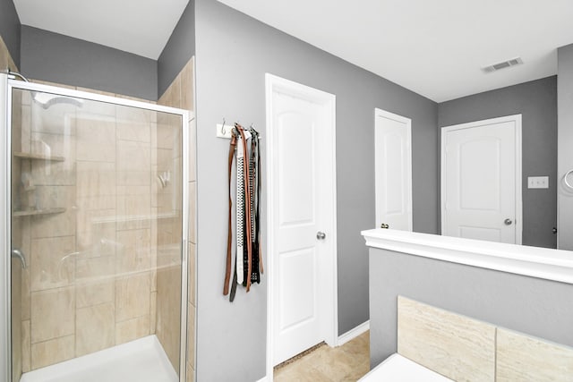 bathroom with a shower with door and tile patterned floors