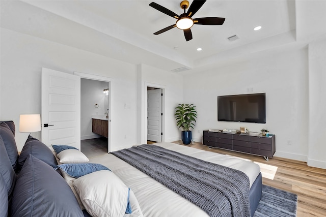 bedroom featuring a raised ceiling, recessed lighting, baseboards, wood finished floors, and visible vents