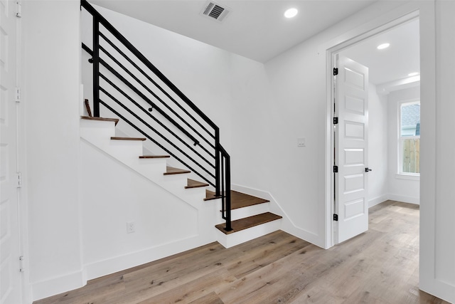 staircase featuring recessed lighting, baseboards, visible vents, and wood finished floors