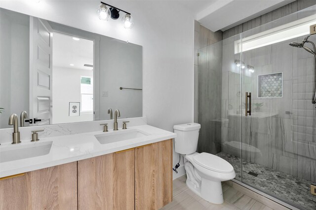 full bath with double vanity, toilet, a sink, and a stall shower