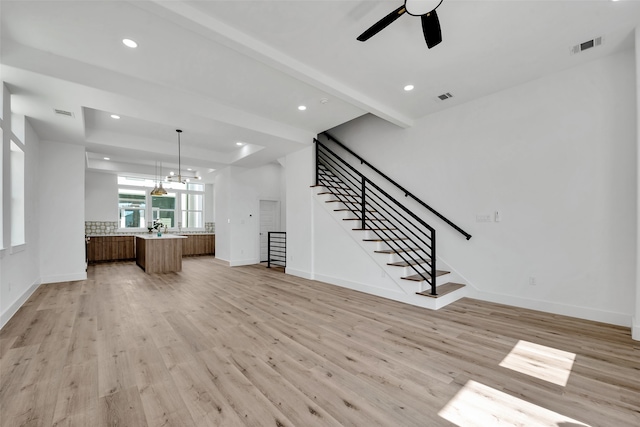 unfurnished living room with baseboards, light wood-style flooring, and stairway