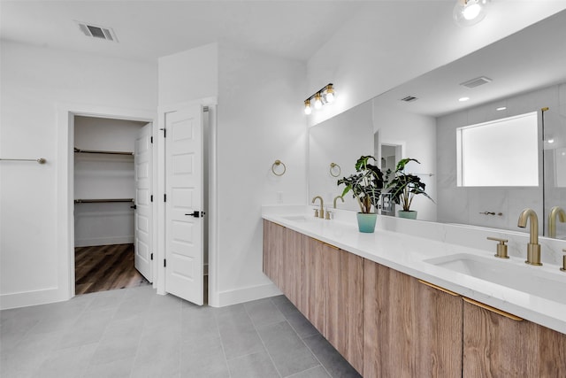 bathroom with a sink, double vanity, and visible vents