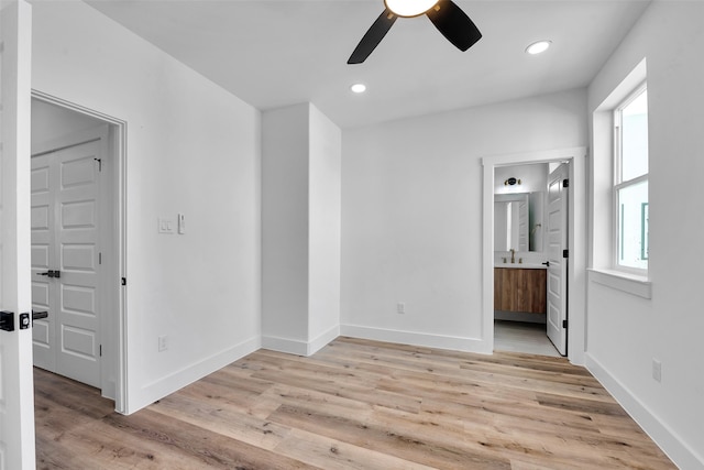 unfurnished bedroom featuring baseboards, multiple windows, and light wood-type flooring