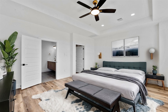 bedroom featuring visible vents, baseboards, light wood-style floors, a tray ceiling, and recessed lighting