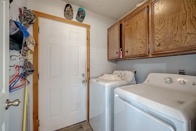 clothes washing area with cabinets, a textured ceiling, washing machine and dryer, and light wood-type flooring