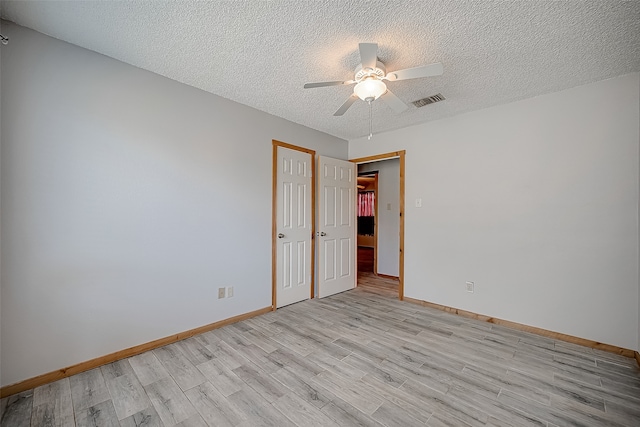 spare room with ceiling fan, light wood-type flooring, and a textured ceiling