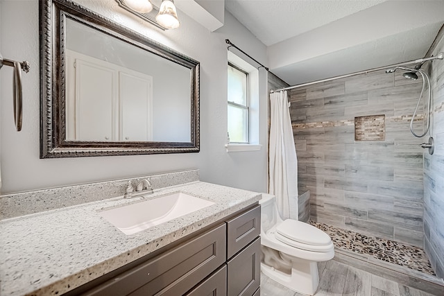 bathroom with vanity, toilet, a textured ceiling, and walk in shower