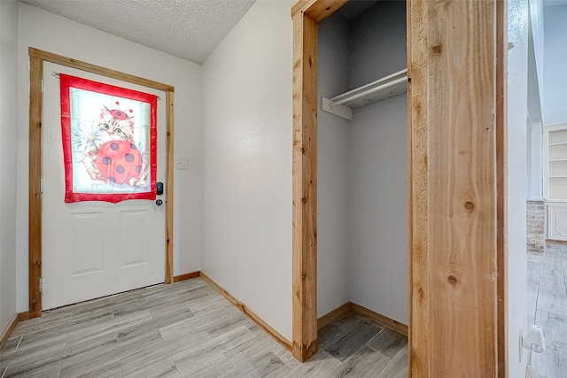 doorway with light hardwood / wood-style floors and a textured ceiling