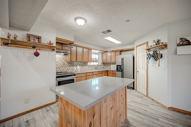 kitchen with backsplash, a textured ceiling, stainless steel appliances, sink, and light hardwood / wood-style floors