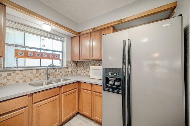 kitchen featuring stainless steel fridge with ice dispenser, a textured ceiling, tasteful backsplash, and sink