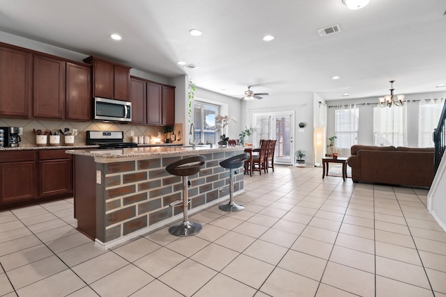 kitchen featuring light stone countertops, a healthy amount of sunlight, range with gas cooktop, and a kitchen island with sink