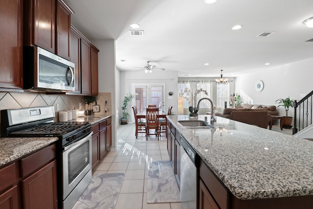 kitchen featuring light tile patterned floors, appliances with stainless steel finishes, backsplash, an island with sink, and sink