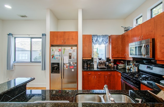 kitchen featuring sink, appliances with stainless steel finishes, hardwood / wood-style flooring, and dark stone countertops