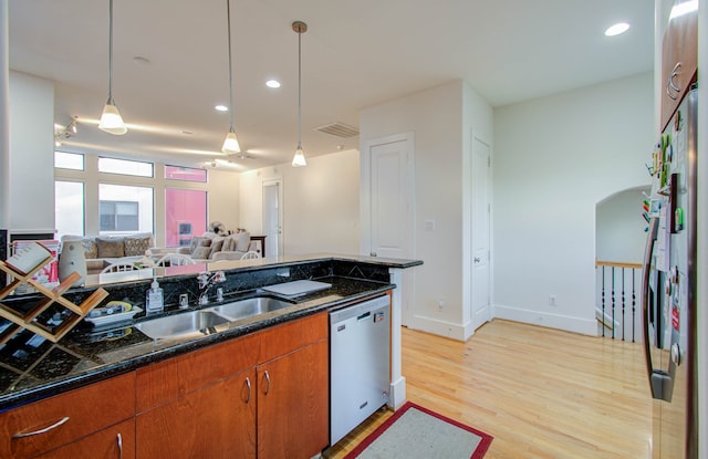 kitchen with light hardwood / wood-style flooring, dishwasher, dark stone countertops, pendant lighting, and sink