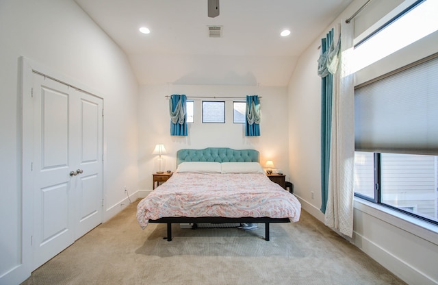 bedroom featuring vaulted ceiling, light carpet, a closet, and ceiling fan