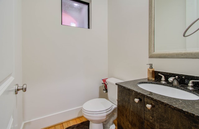 bathroom with toilet, hardwood / wood-style floors, and vanity