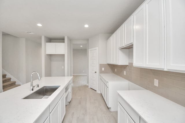 kitchen featuring sink, white cabinets, decorative backsplash, and light hardwood / wood-style floors