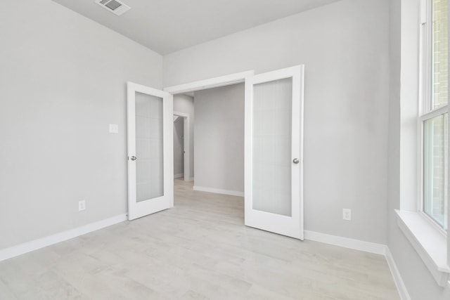 unfurnished bedroom with french doors, multiple windows, and light hardwood / wood-style floors