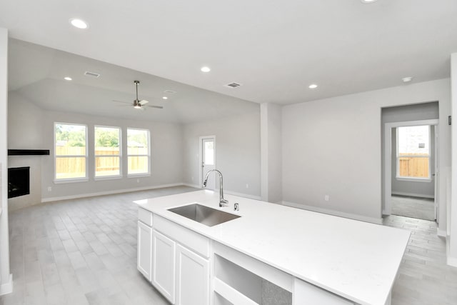 kitchen with white cabinetry, sink, a wealth of natural light, and a center island with sink