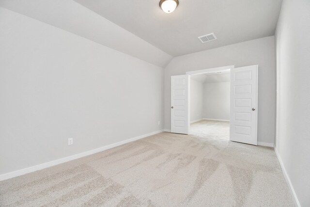 unfurnished bedroom with light carpet and lofted ceiling