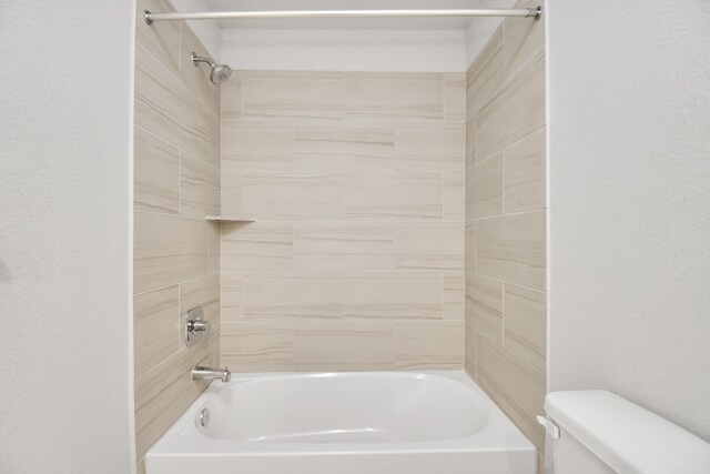 bathroom featuring tiled shower / bath and toilet