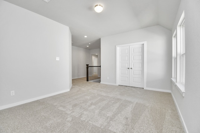 unfurnished bedroom featuring a closet, lofted ceiling, and light colored carpet