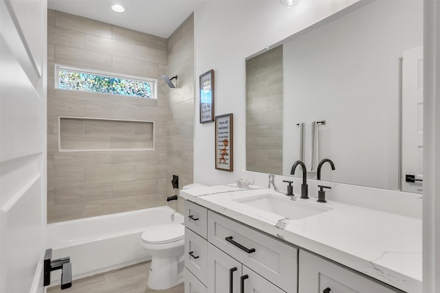 full bathroom with hardwood / wood-style floors, vanity, tiled shower / bath combo, and toilet