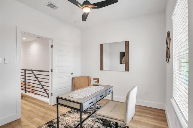 office with light wood-type flooring and ceiling fan