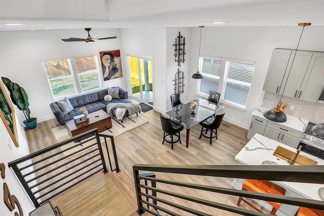 living room with light wood-type flooring, ceiling fan, and lofted ceiling