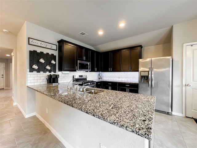 kitchen featuring light stone counters, stainless steel appliances, tasteful backsplash, and kitchen peninsula