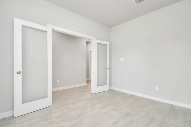 unfurnished bedroom with light hardwood / wood-style floors, a closet, and french doors