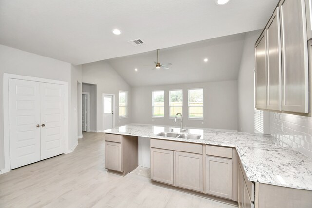 kitchen with tasteful backsplash, sink, vaulted ceiling, light hardwood / wood-style floors, and kitchen peninsula