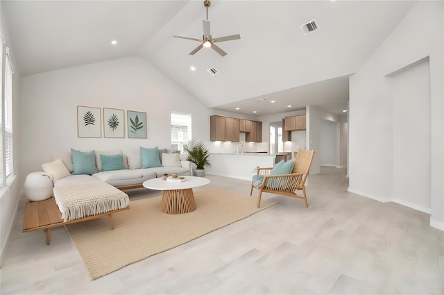 living room with light hardwood / wood-style floors, ceiling fan, and high vaulted ceiling