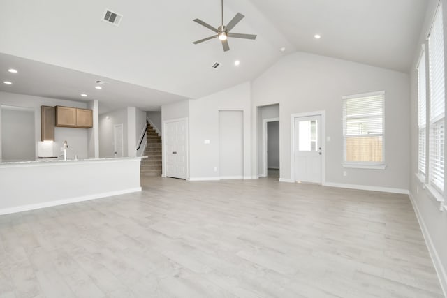 unfurnished living room with high vaulted ceiling, light hardwood / wood-style floors, ceiling fan, and sink