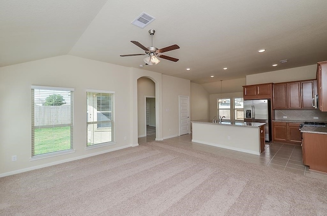 kitchen featuring a wealth of natural light, a kitchen island with sink, carpet, and stainless steel appliances