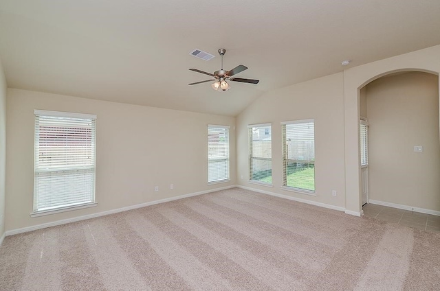 spare room featuring light carpet, ceiling fan, a healthy amount of sunlight, and vaulted ceiling