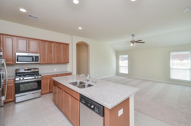 kitchen with stainless steel appliances, sink, an island with sink, lofted ceiling, and light tile patterned flooring