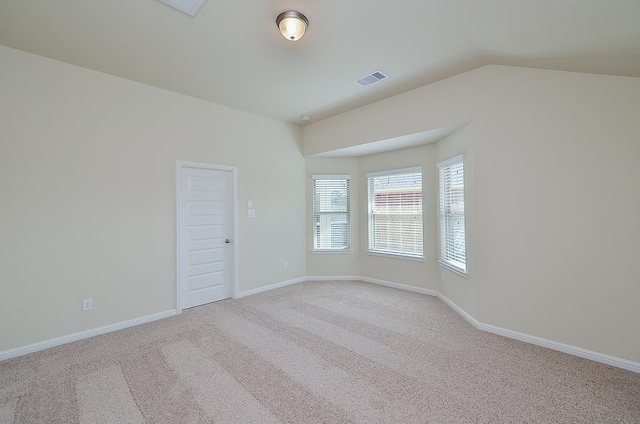 spare room with light colored carpet and vaulted ceiling