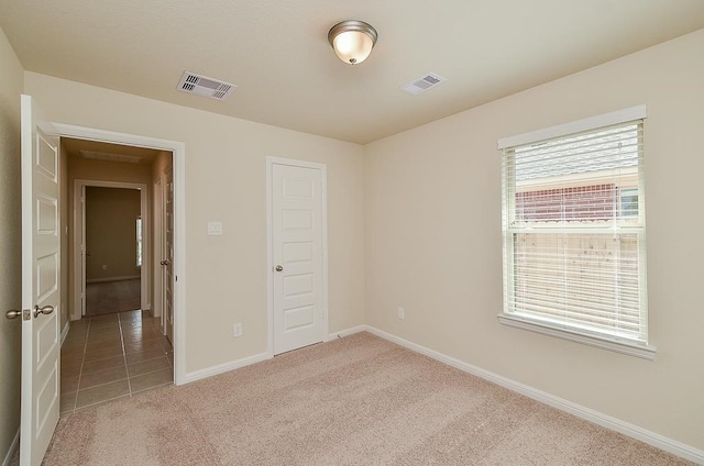 unfurnished bedroom with a closet and light colored carpet