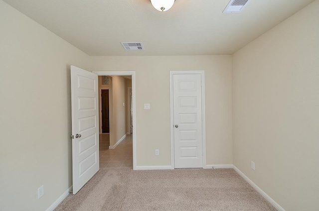 unfurnished bedroom with a closet and light colored carpet