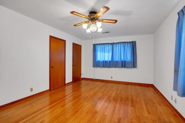 unfurnished bedroom featuring multiple closets, light wood-type flooring, and ceiling fan