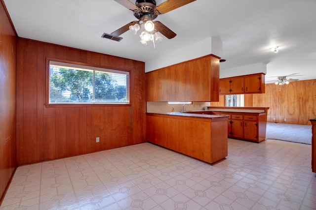 kitchen featuring wooden walls, kitchen peninsula, and ceiling fan